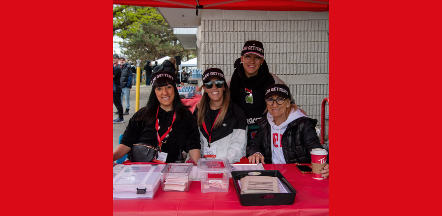 Volunteers at a Muscular Dystrophy Canada fundraising event wearing "Go Getter's" hats and welcoming participants at a registration table.