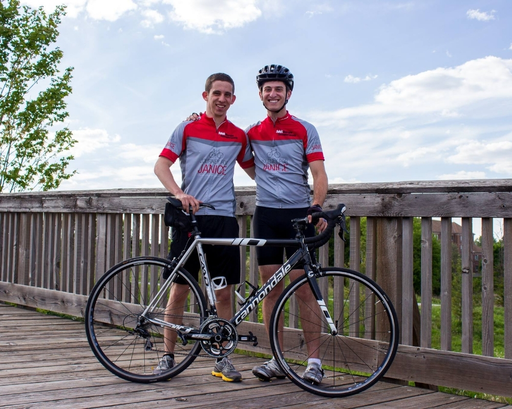 Jordan Freedman and his teammate stand in front of their street bike wearing grey and red uniforms.