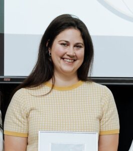 Headshot of dark haired woman holding a framed photo award.