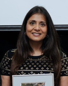 Headshot of dark haired woman holding a framed photo award.