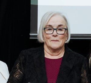 Headshot of grey haired woman holding a framed photo award.